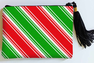 Colorful zip pouch with diagonal red and green stripes and white accents, black zipper, and a black tassel on the side.