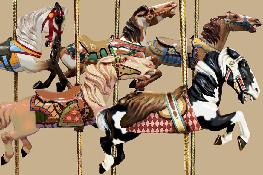 Colorful carousel horses in mid-gallop with ornate saddles and brass poles against a beige background.